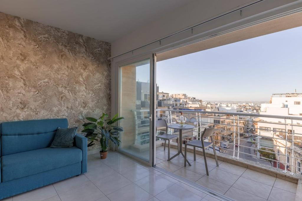 un soggiorno con divano blu e balcone di The Pinnacle Fl6 a Mellieħa