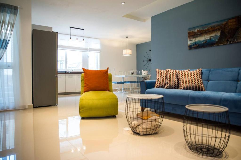 ein Wohnzimmer mit einem blauen Sofa und einem gelben Stuhl in der Unterkunft Modern 1br Maisonette 2 Mins Away From The Beach in St Paul's Bay