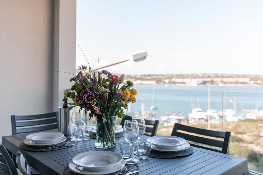 uma mesa com pratos e um vaso de flores em Luxe 3br Melliehabay Retreat And Stunning Terrace em Mellieħa