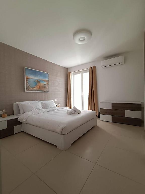 a white bedroom with a large bed and a window at Cosy 2bed Apartment In Manikata By Homely in Mellieħa