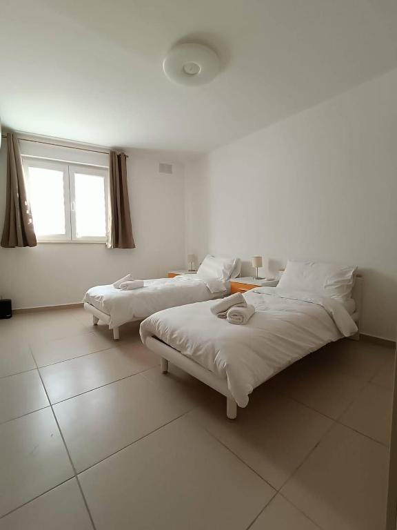 two beds in a white room with a window at Cosy 2bed Apartment In Manikata By Homely in Mellieħa