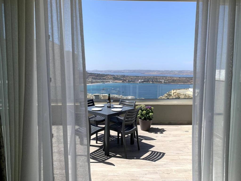 einen Tisch und Stühle auf einem Balkon mit Aussicht in der Unterkunft Lovely Penthouse In Mellieha-seaview in Mellieħa