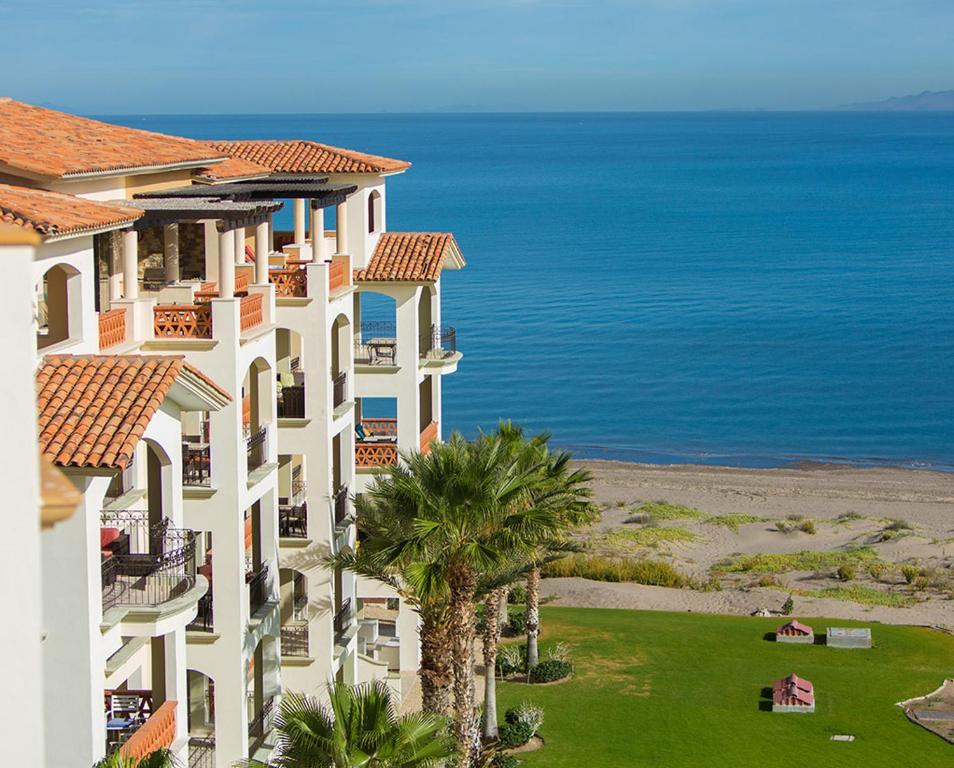 uma vista para um edifício com palmeiras e o oceano em Paraiso del Mar Condominiums em Misiones de La Paz