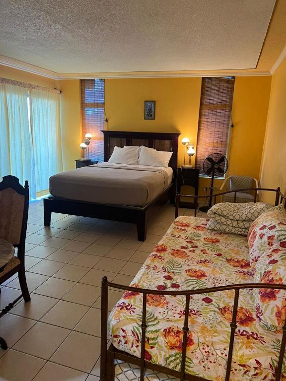 a bedroom with two beds and two chairs in it at Sunny Tides at Montego Bay Club Resort in Montego Bay