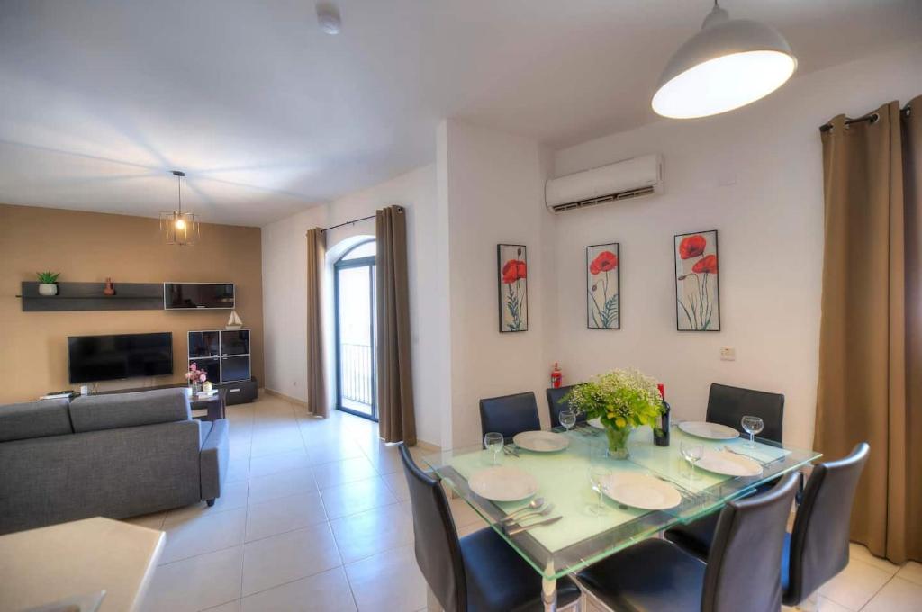 een eetkamer en een woonkamer met een tafel en stoelen bij Jonathan Cassar St Julians Lovely 3 Bedrooms in Taʼ Ċikkun