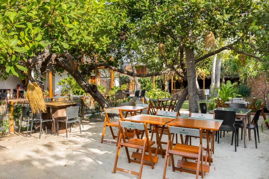 a group of tables and chairs under a tree at Rancharia Charme Beach in Atins