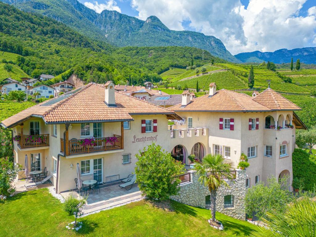 una casa in un villaggio con montagne sullo sfondo di Leuchtenhof a Caldaro