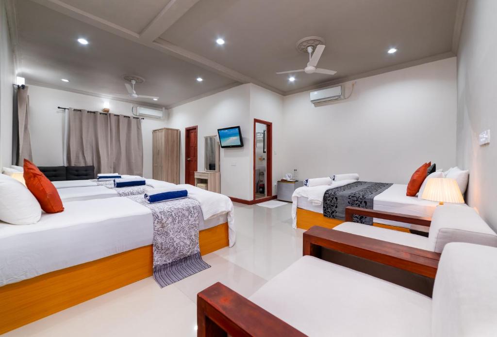 een kamer met 2 bedden, een bank en een tv bij Palm Oasis at Ukulhas in Ukulhas