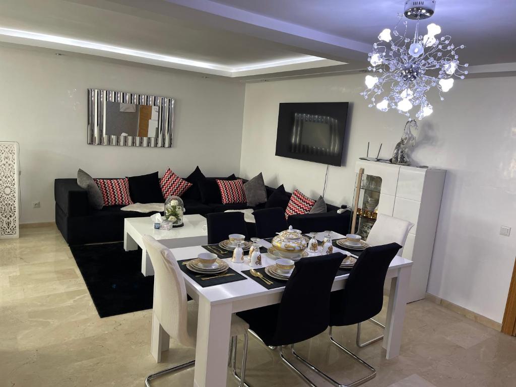 un soggiorno con tavolo bianco e divano nero di Luxueux appart à côté aéroport a Nouaceur