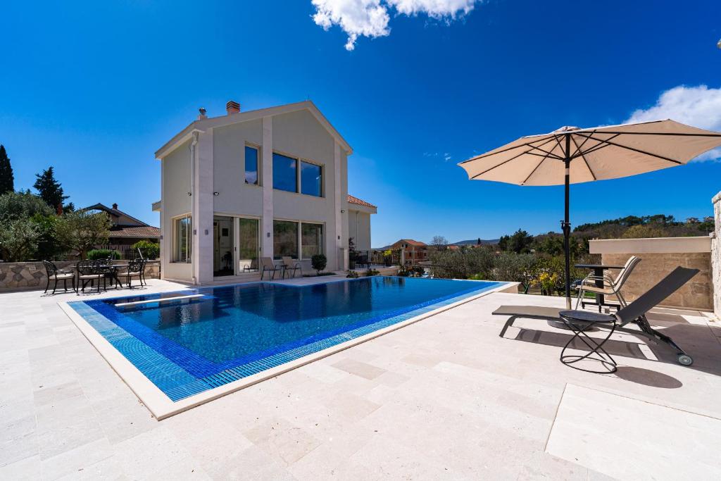 eine Villa mit Swimmingpool und Sonnenschirm in der Unterkunft Majestic Apartment in Tivat
