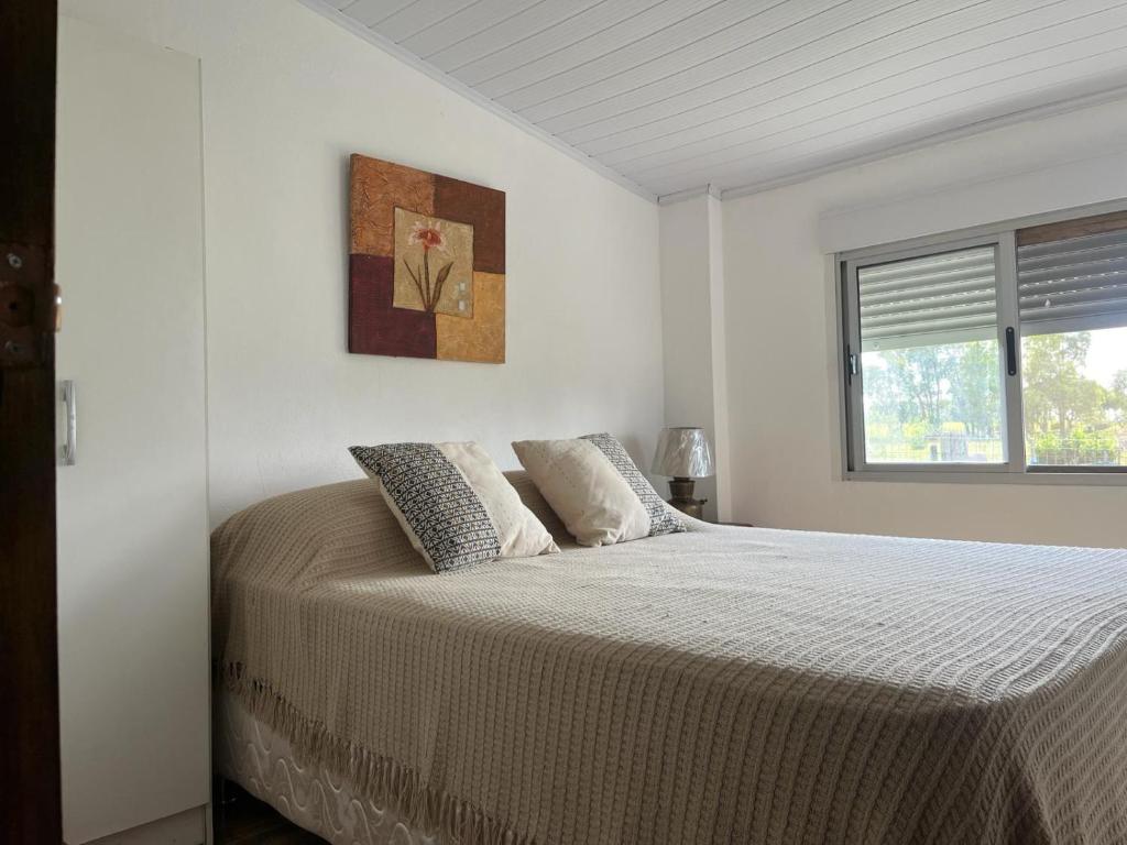 um quarto branco com uma cama grande e 2 almofadas em 0 es 3 Uno em Treinta y Tres