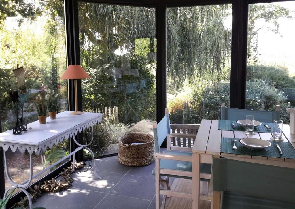 een patio met een tafel en stoelen en een groot raam bij Résidence P-pleumeur Bodou - Maisons & Villas 494 in Pleumeur-Bodou