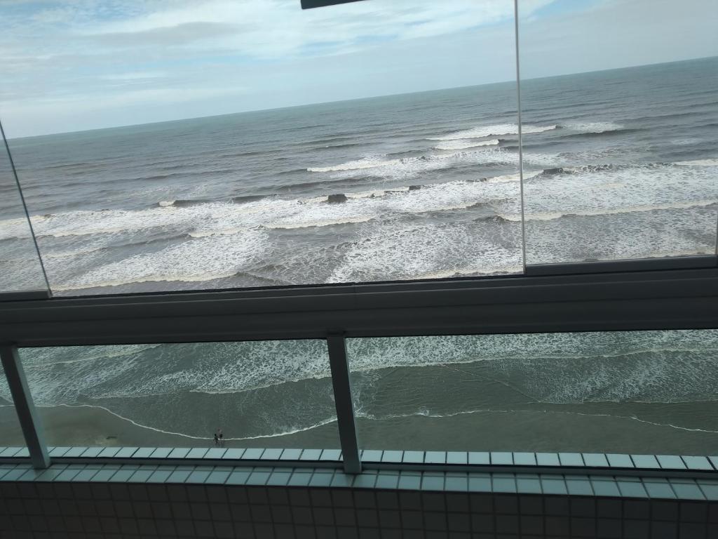 uma vista para o oceano a partir de uma janela em Apartamento frente mar pé na areia na Praia Grande