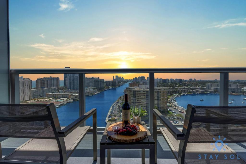 a table with a bottle of wine on top of a balcony at Infinite View Balcony - Amazing Pool - Gym in Hallandale Beach