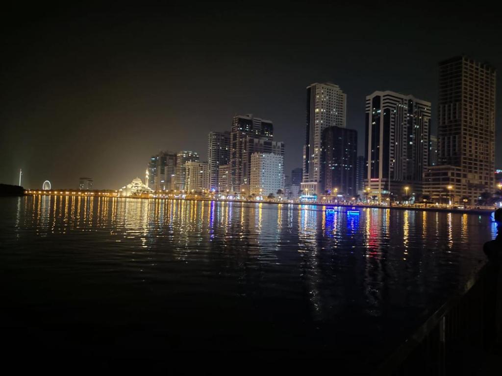 un perfil urbano por la noche con el agua y los edificios en Arnim Suite - 3 Bedrooms Apartment, en Sharjah