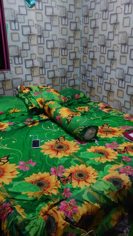 a bed with a green comforter with bees on it at RISKY HOUSE in Sampit