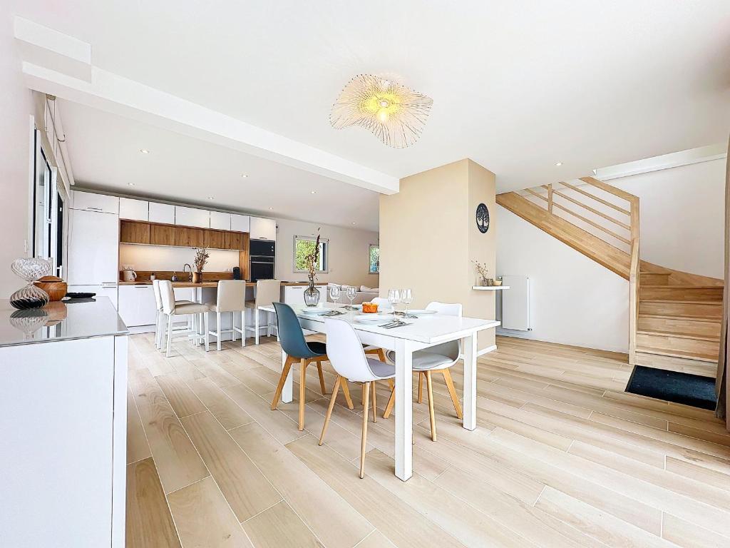 une salle à manger et une cuisine avec une table et des chaises blanches dans l'établissement Le Ruffa, à Bohars