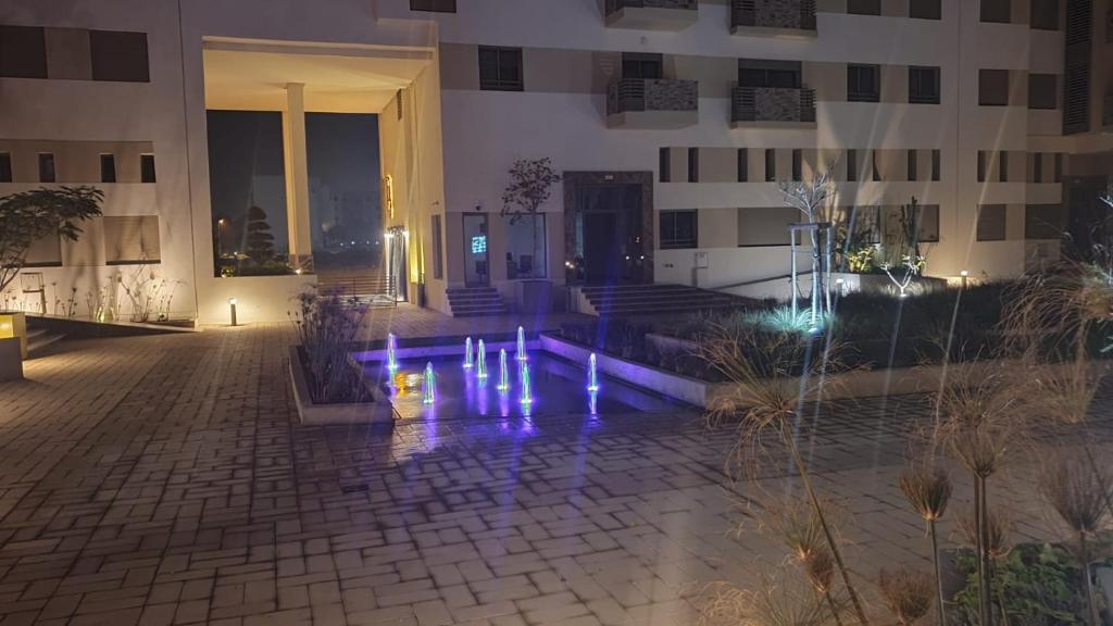 Property management aéroport med V international في Dah Hammou Ben Cheïkh: مبنى به أضواء أرجوانية في ساحة الفناء في الليل