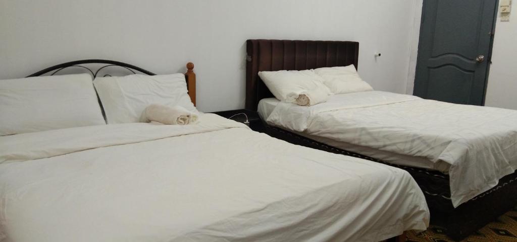 dos camas sentadas una al lado de la otra en una habitación en Melrose homestay and transport, en Kampong Kiarong