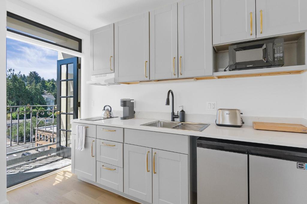a kitchen with white cabinets and a view of a balcony at Norblad Hotel in Astoria, Oregon