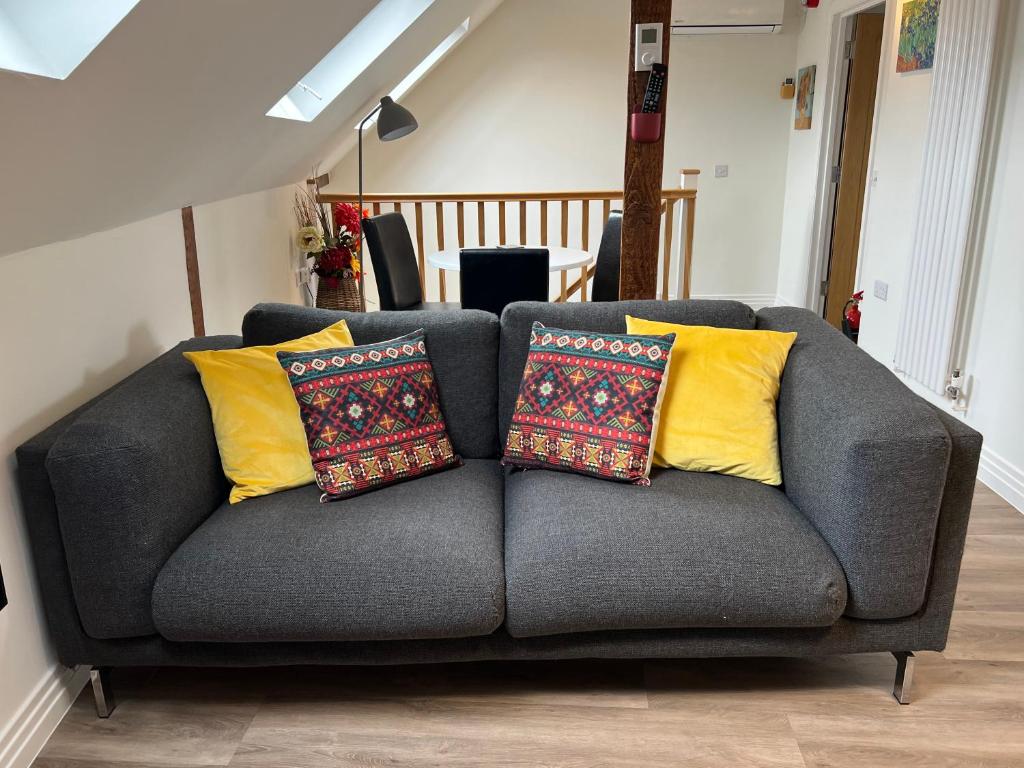 ein graues Sofa mit gelben Kissen im Wohnzimmer in der Unterkunft Glastonbury Town Centre - Split-Level 1 Bedroom Apartment in Glastonbury