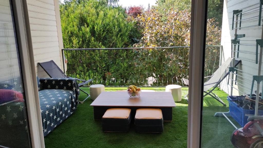 a patio with a table and a chair on the grass at Homestay chez Lien proche RER B in Bures-sur-Yvette