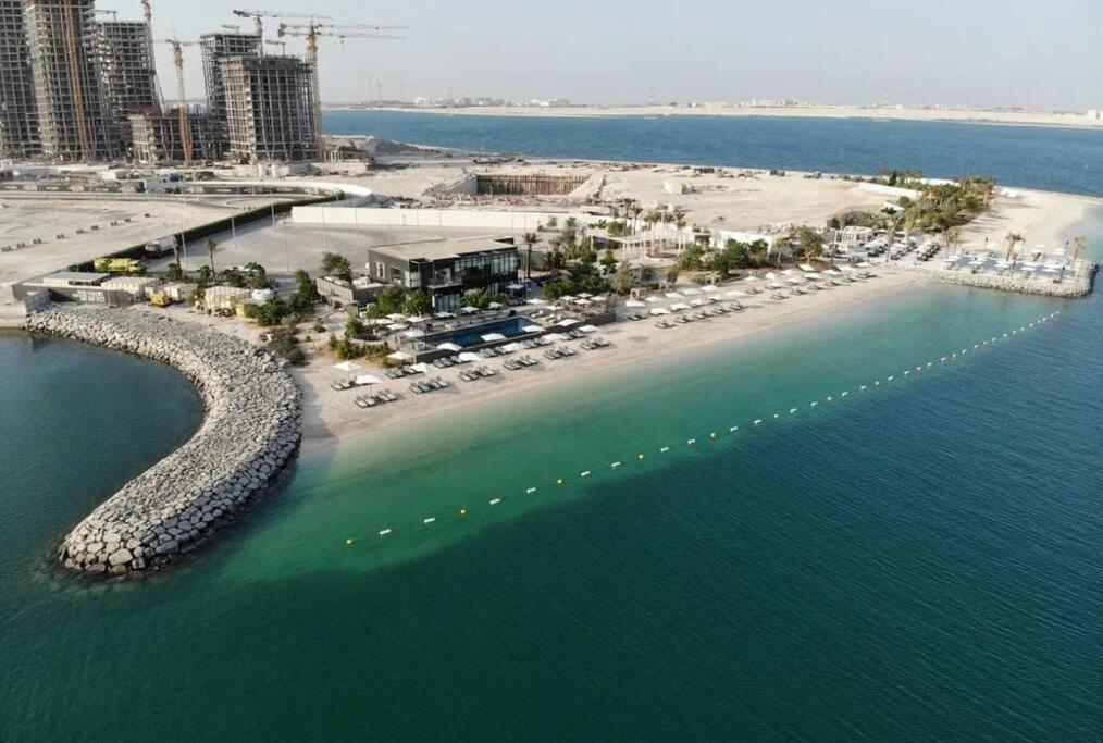 eine Luftansicht auf einen Strand mit Sonnenschirmen und dem Meer in der Unterkunft Dutch Luxury Apartment - Private Beach in Abu Dhabi