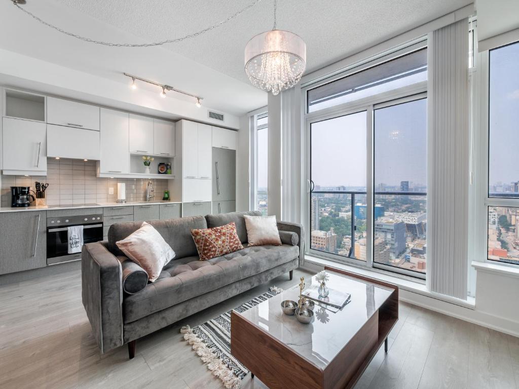 Designer One Bedroom Suite - Entertainment District Toronto في تورونتو: غرفة معيشة مع أريكة وطاولة
