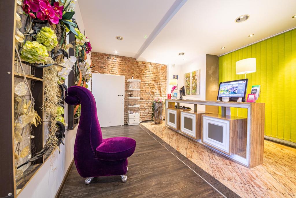 een woonkamer met een paarse stoel en een televisie bij ArtHotel City in Neurenberg
