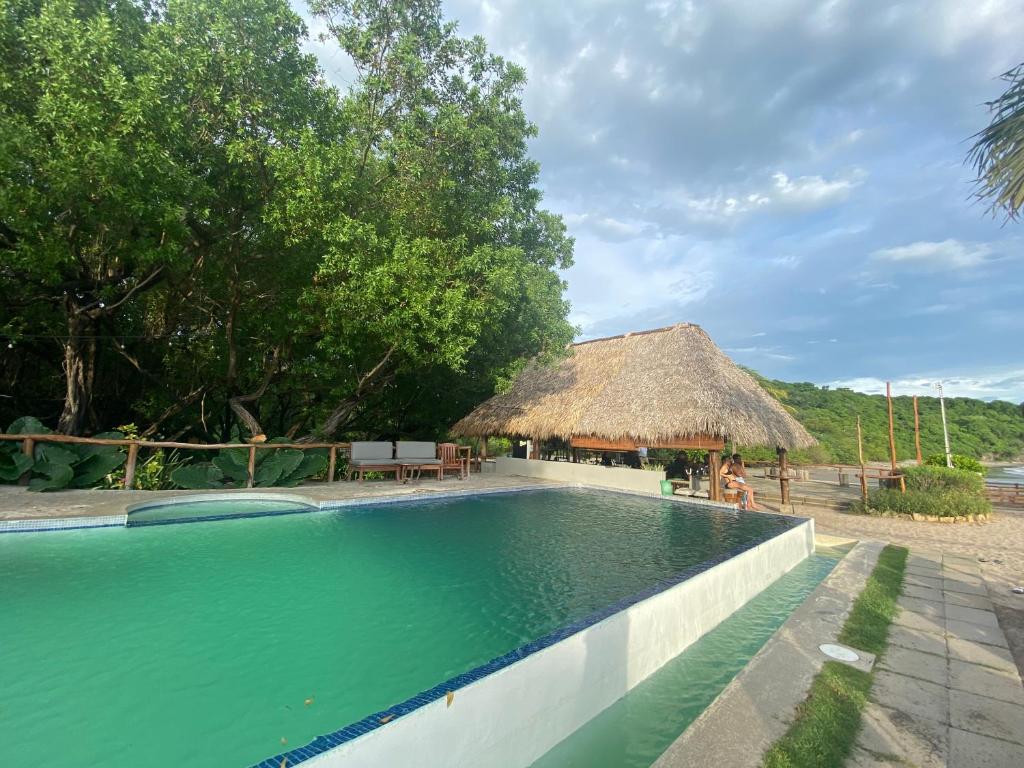a swimming pool at a resort with a thatch hut at Hacienda Iguana Cesars Colarado in Tola