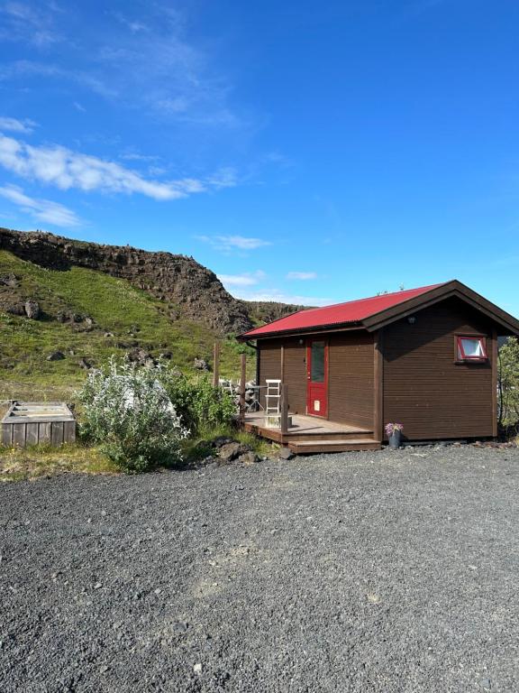 a small cabin with a red door on a hill at Hlíðarás Guesthouse in Ölfus