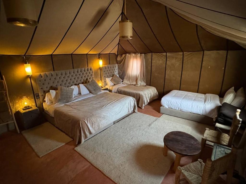a bedroom with two beds in a tent at Erg Chebbi Sahara Camp in Merzouga