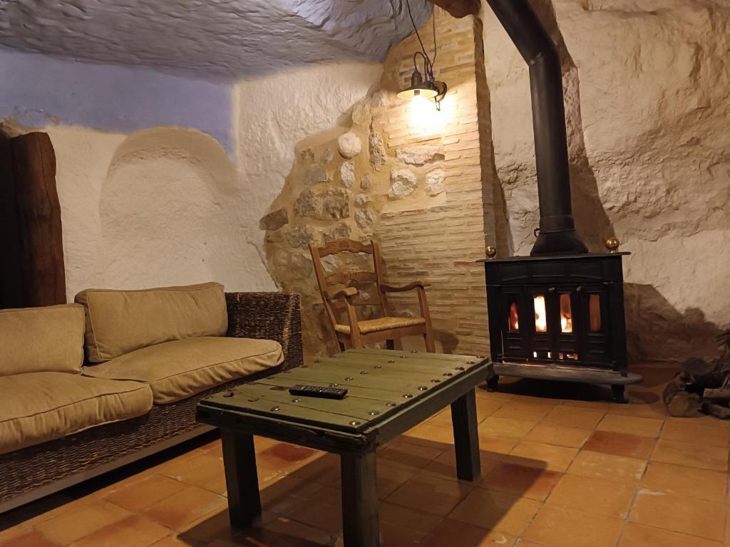 sala de estar con sofá y estufa de leña en La Cueva Colosal, en Alcalá del Júcar