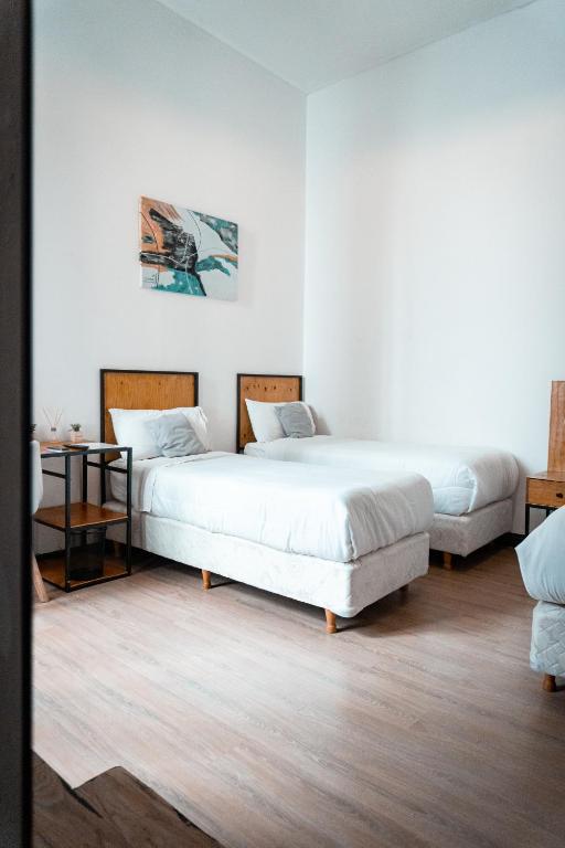 two beds in a room with white walls and wooden floors at Hostel Sweet Home Palermo Soho in Buenos Aires