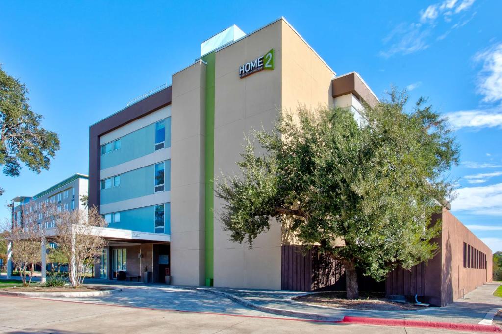 an office building with a tree in front of it at Home2 Suites by Hilton Austin/Cedar Park in Cedar Park