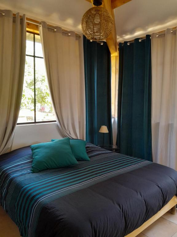 1 dormitorio con 1 cama grande y cortinas azules en Domaine d'Avalon, en Lorgues