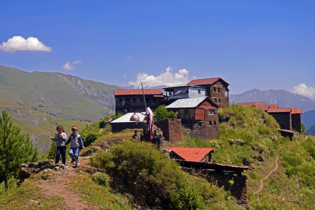 two children walking on a hill with a building at paradise of tusheti in Omalo
