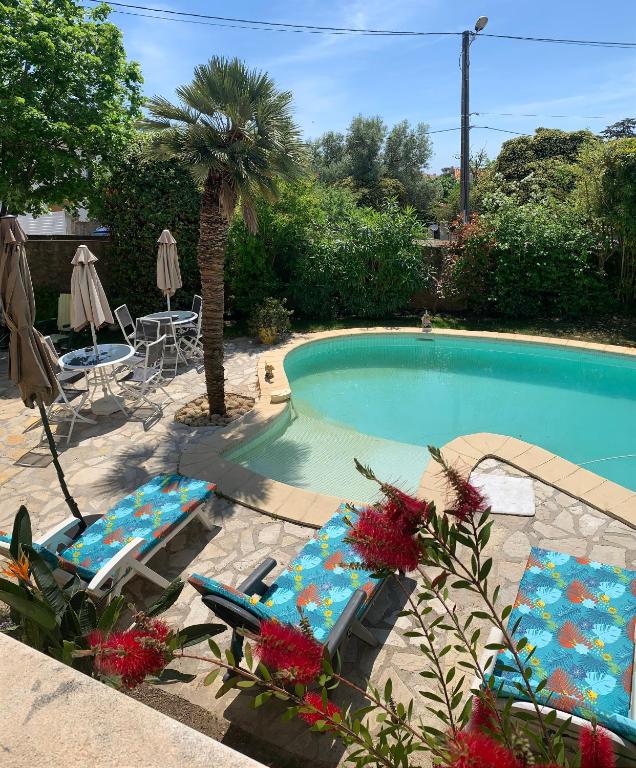 a swimming pool with two lounge chairs and a table at Deux chambres dans villa proche de la plage in Sète