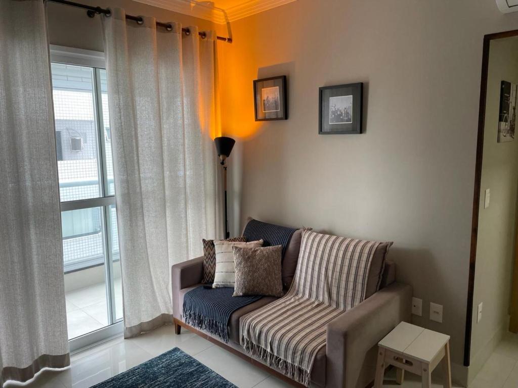 a living room with a couch and a large window at Santos Linda!! Apartment for Business and Leisure. in Santos