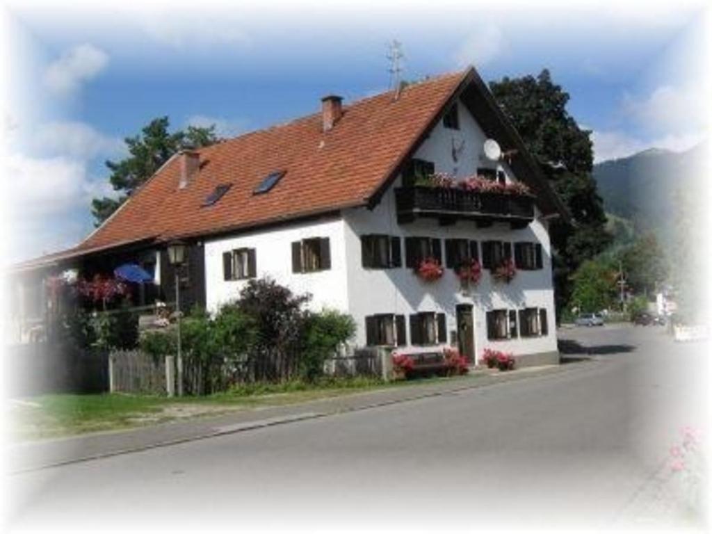 uma casa branca com um telhado vermelho e flores em Ferienwohnung für 4 Personen 1 Kind ca 50 qm in Unterammergau, Bayern Oberbayern em Unterammergau