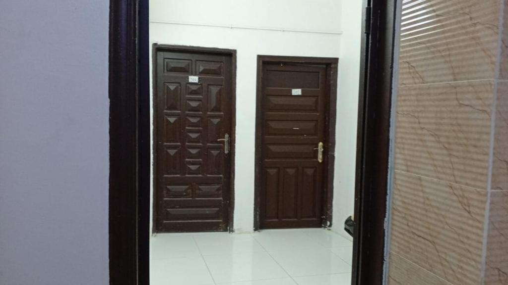 two brown doors in a room with a tile floor at غرف مجاورين المصطفى رباعي in Medina