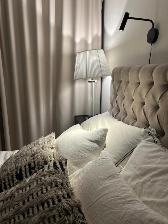a bedroom with a bed with white pillows and a lamp at Trekker's Haven: Noux National Park Retreat in Espoo