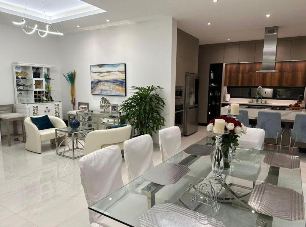a dining room and kitchen with a glass table and white chairs at casa en samborondon in Guayaquil