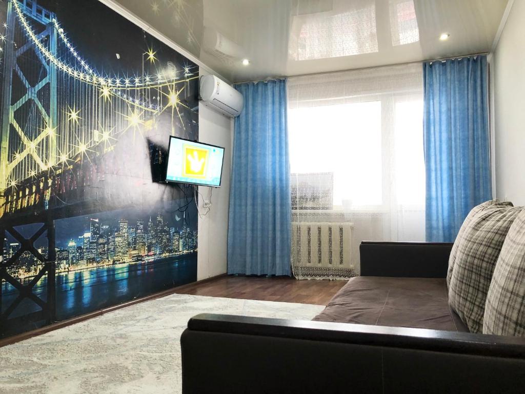 a living room with a tv on a wall at Уютные апартаменты рядом с Ситицентром in Uralsk