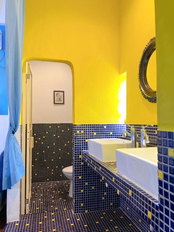a yellow bathroom with two sinks and a toilet at Greek Frontier Villa in Magong