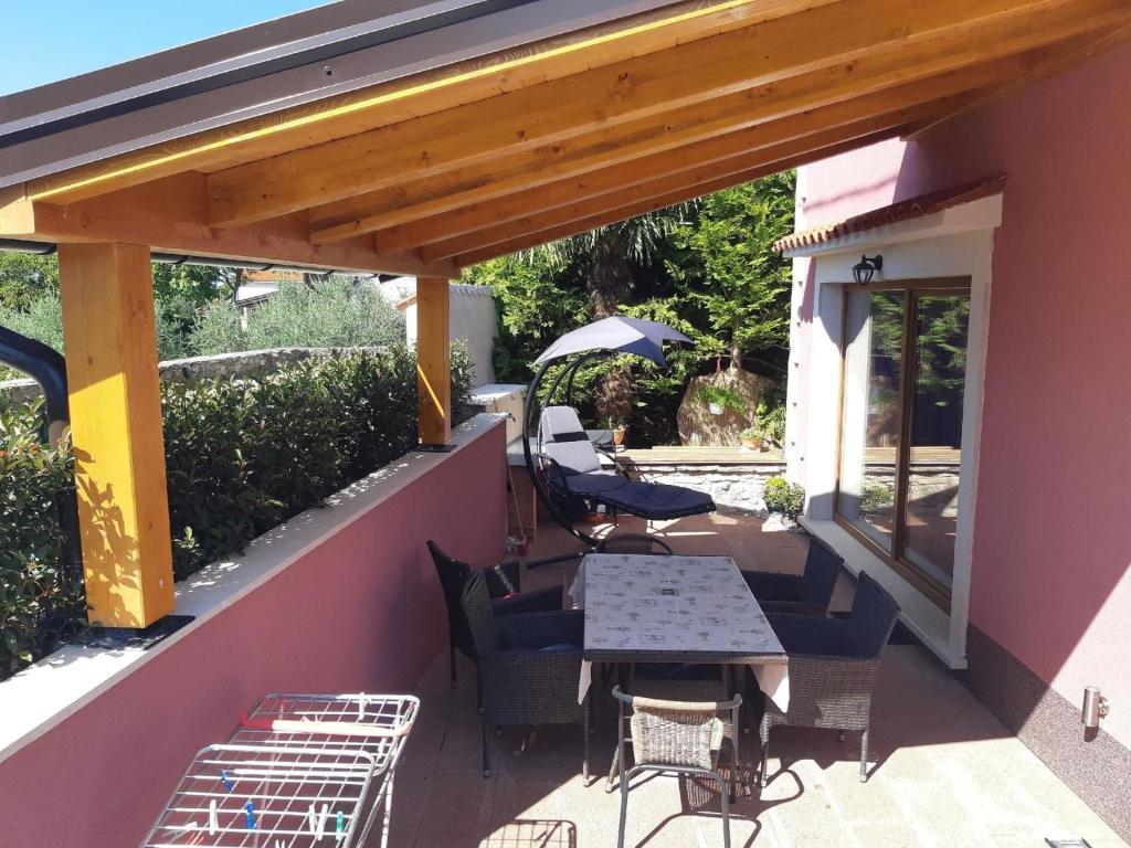 eine Terrasse mit einem Tisch, Stühlen und einem Sonnenschirm in der Unterkunft Ferienwohnung mit Terrasse für sechs Personen in Bale