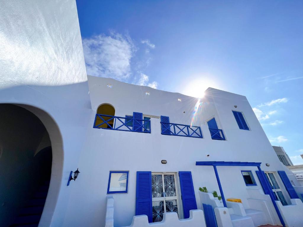 ein weißes Gebäude mit blauen Fensterläden und der Sonne in der Unterkunft Greek Frontier Villa in Magong