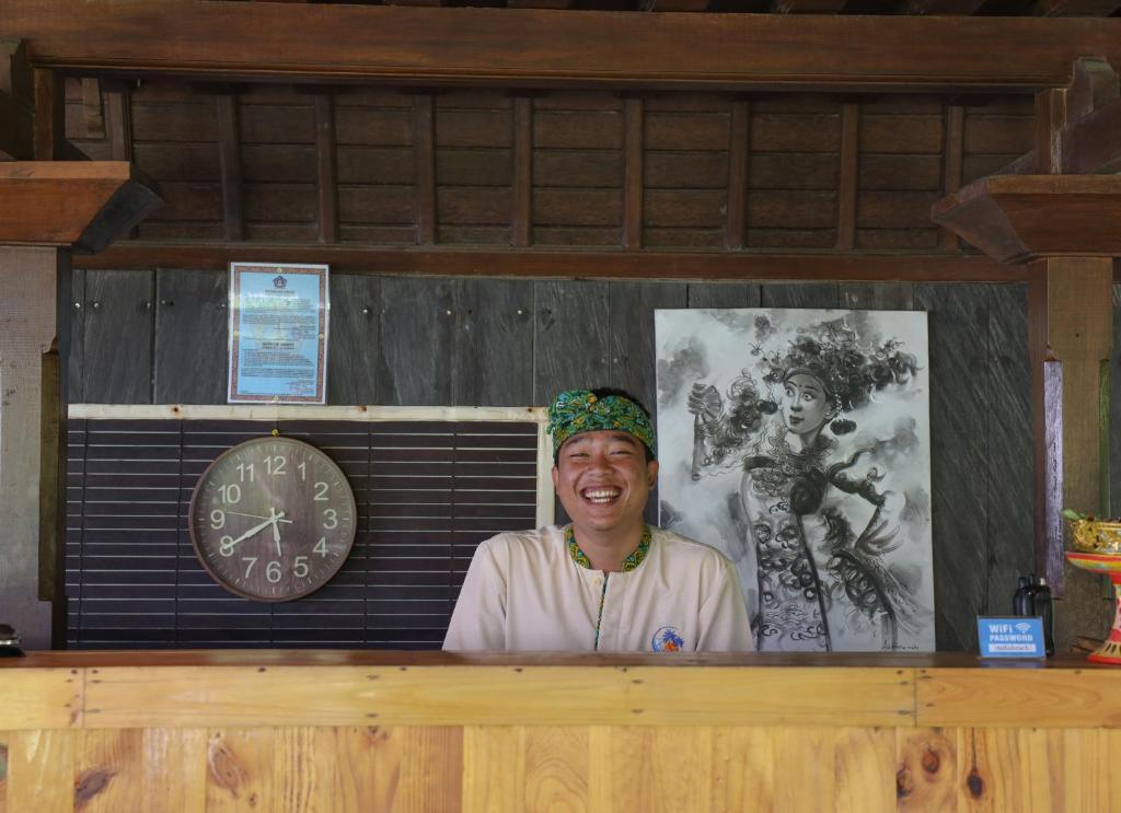 a man standing behind a counter with a clock at Bali Natha Beach Front in Canggu