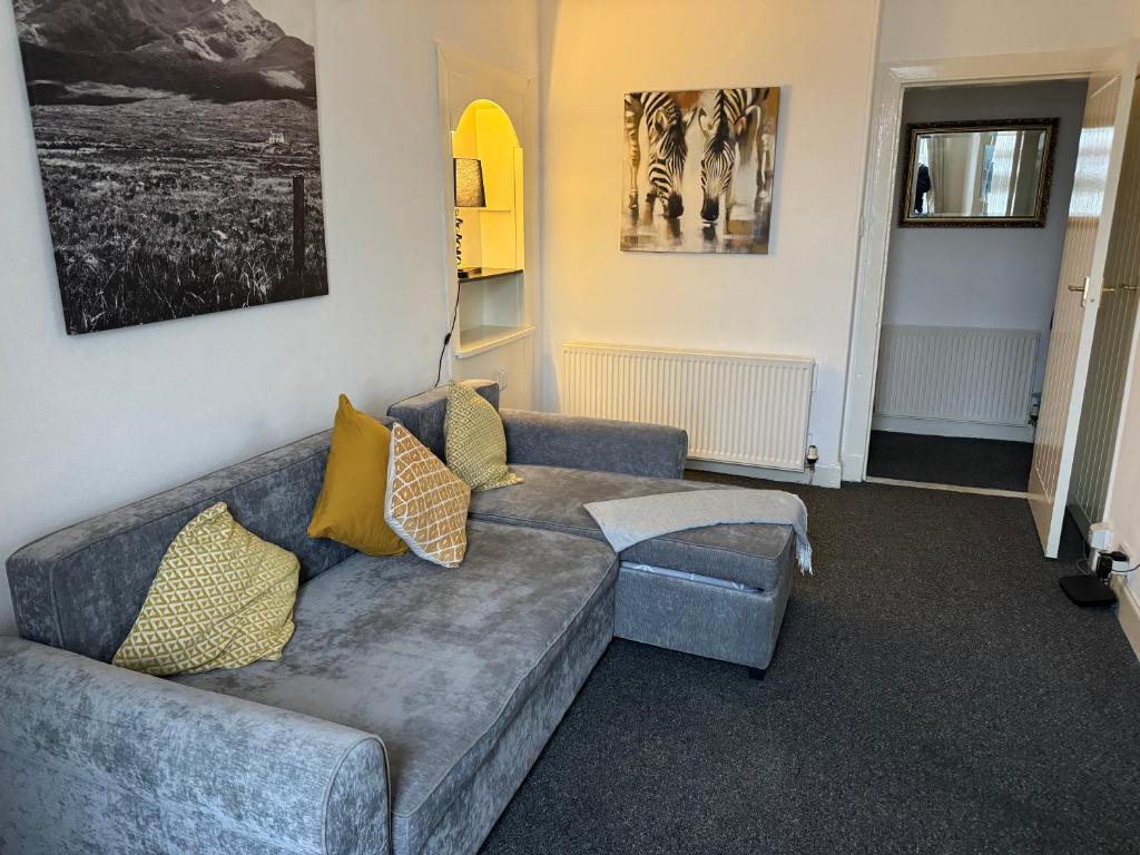 a living room with a gray couch with yellow pillows at 140 MAIN ST GROUND LEFT in Largs