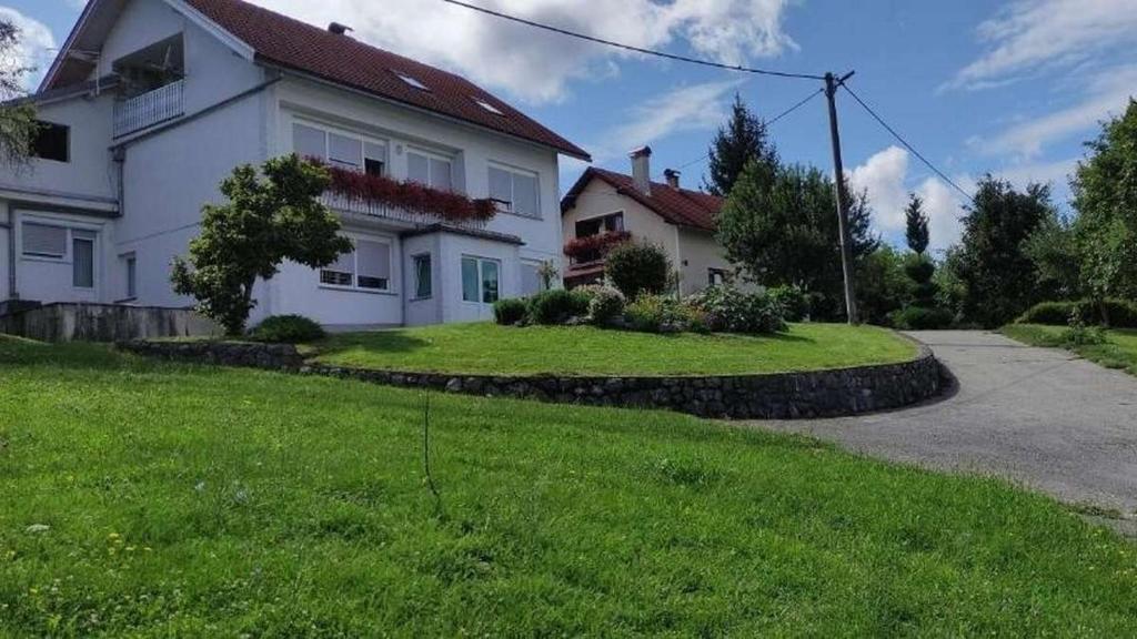 een groot wit huis met een grasveld bij Apartments with a parking space Slunj, Plitvice - 22111 in Slunj